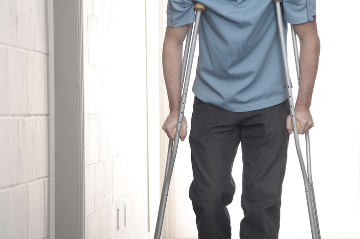 young man with blue shirt walking with crutches
